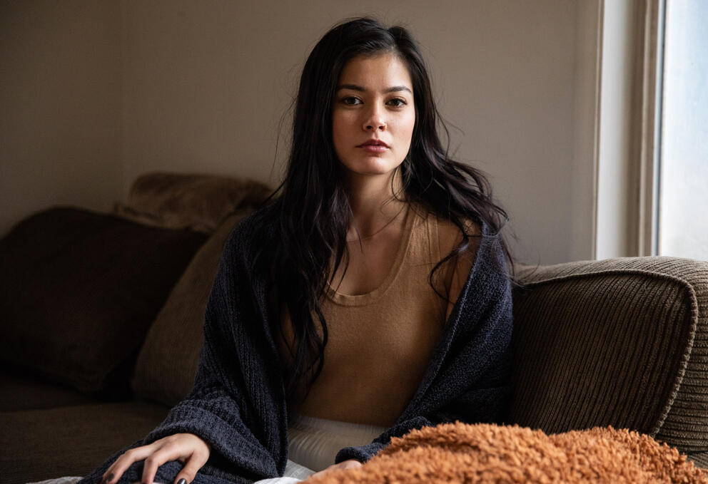 A portrait of a woman on a couch next to a window