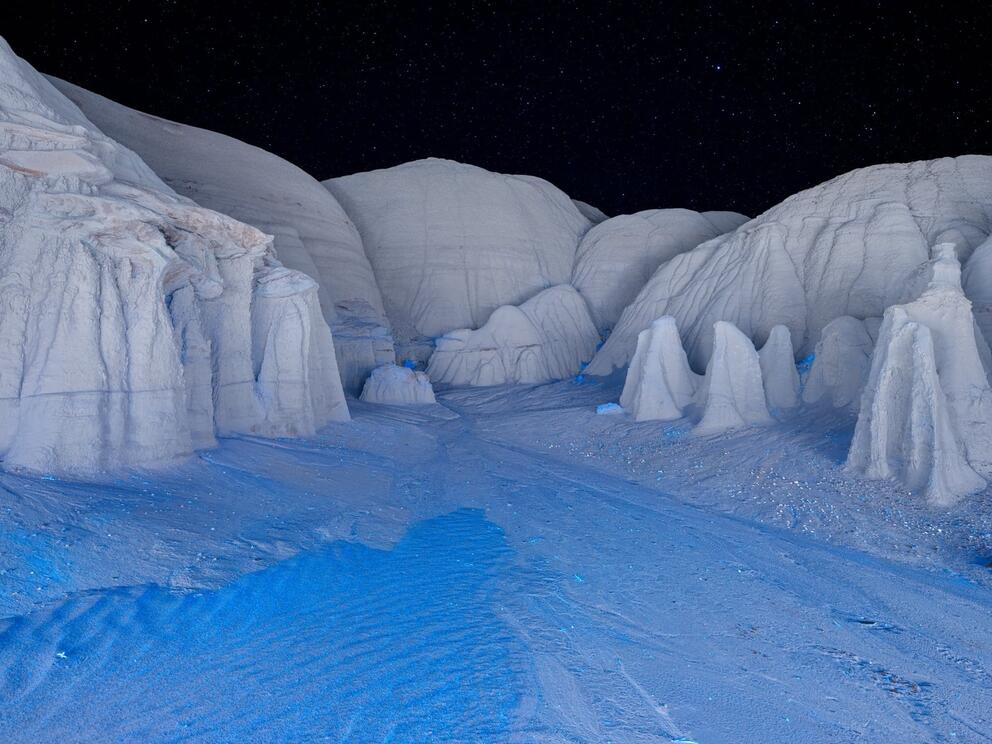 photograph of what looks like white mountains with an ice blue river in the foreground