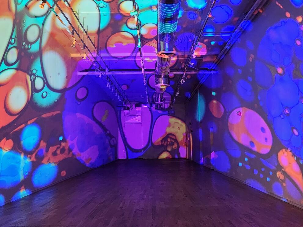 photo of a long empty room lit with lavalamp-like blobs of color