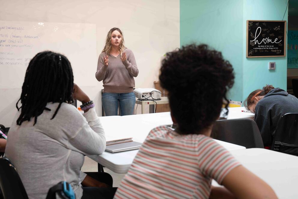 A person leads a class from the front of a classroom.