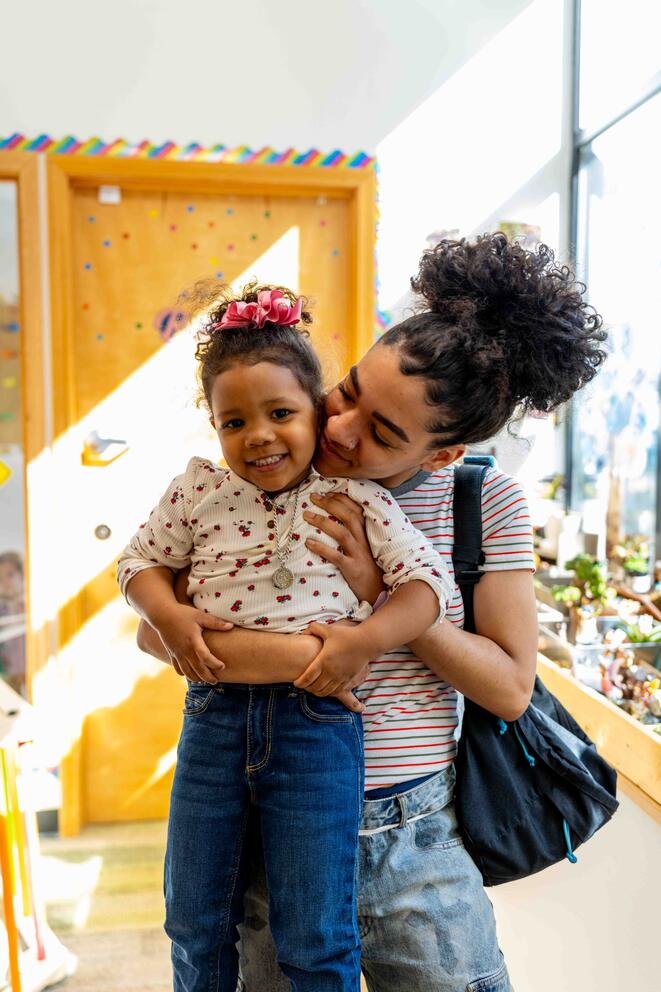 An adult holds a smiling toddler.