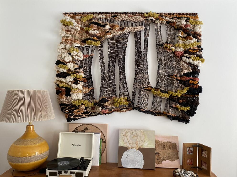 photo of a woven tapestry with black threads and organic puffs of green
