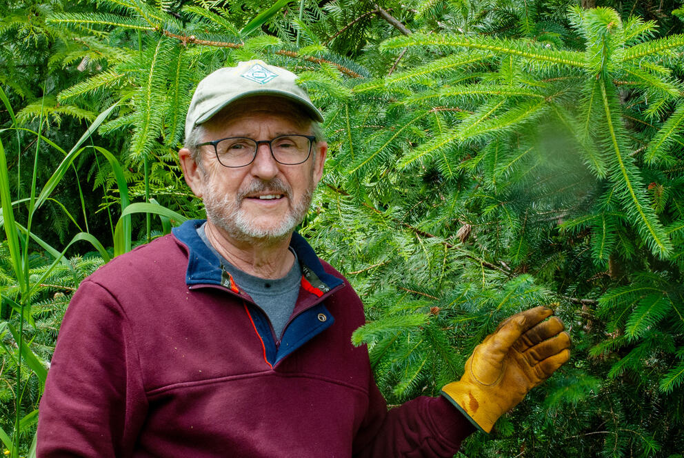 A person poses for a portrait next to a tree.