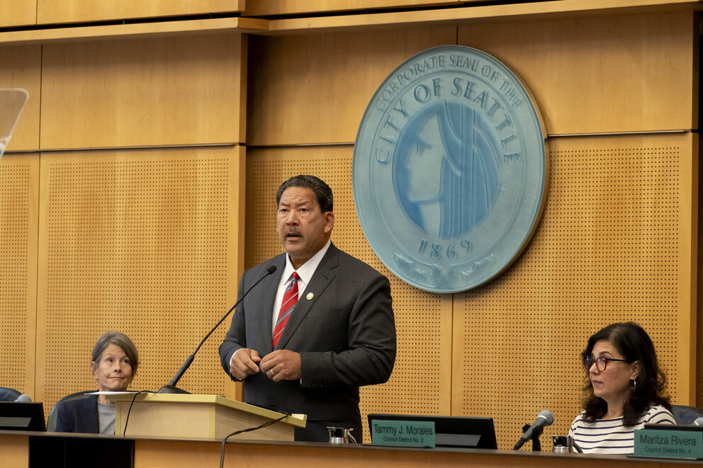 mayor harrell stands at the council podium between councilmembers sara nelson and tammy morales