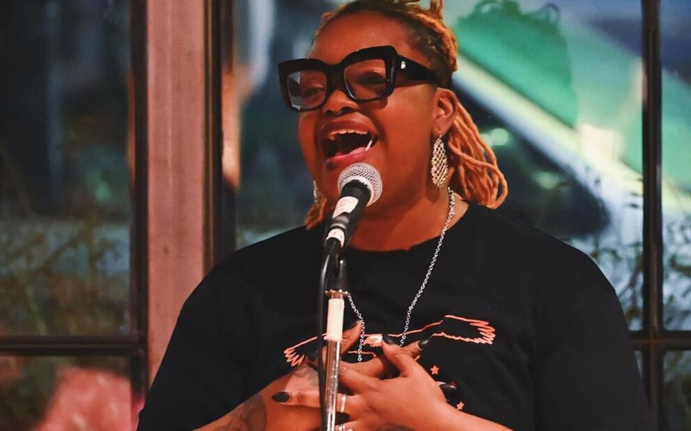a woman in stylish black-rimmed glasses sings at a microphone