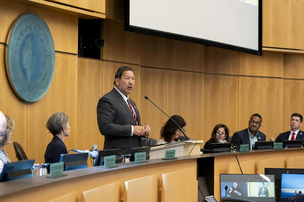 mayor harrell gives his speech in city council chambers surrounded by councilmembers