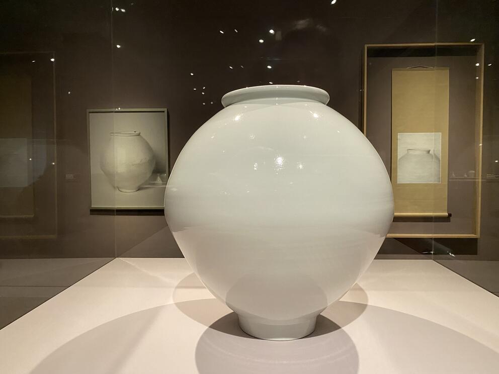 photo of a large white spherical ceramic "moon jar" in a gallery setting