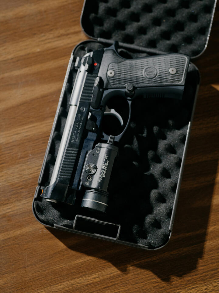 A pistol lays in a traditional handgun lock box.