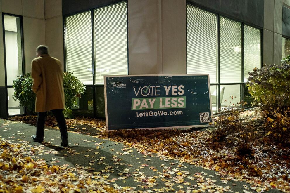 A sign in front of a  building says "Vote Yes Pay Less LetsGoWa.com"