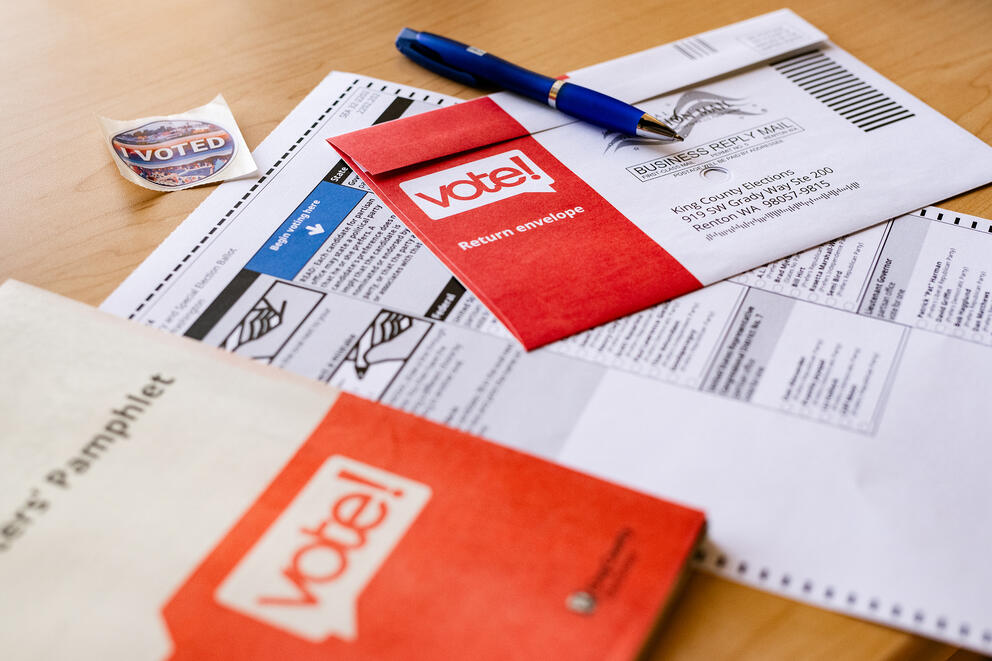 a pile of ballots, envelopes and a voter guide