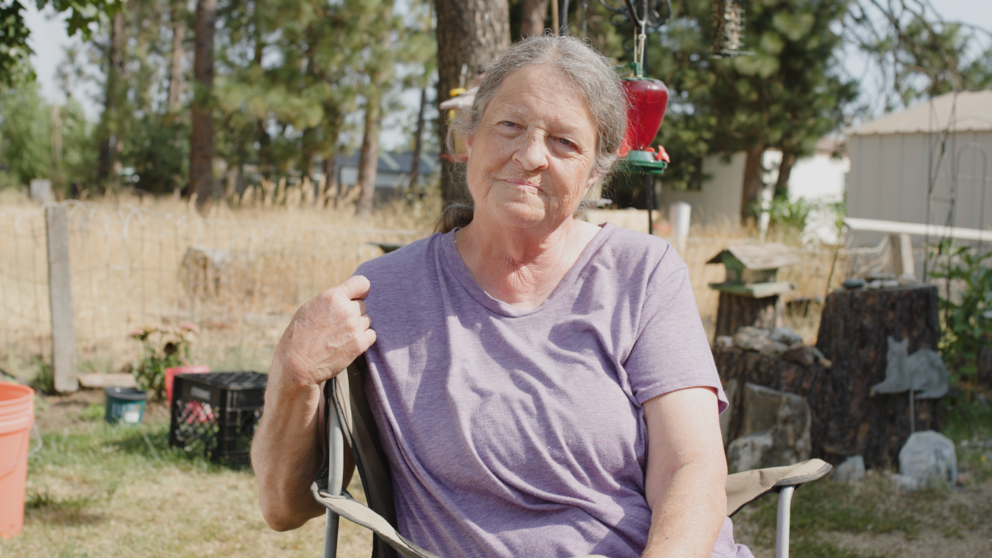 Chandler sits in a chair for an interview with trees and brush behind her