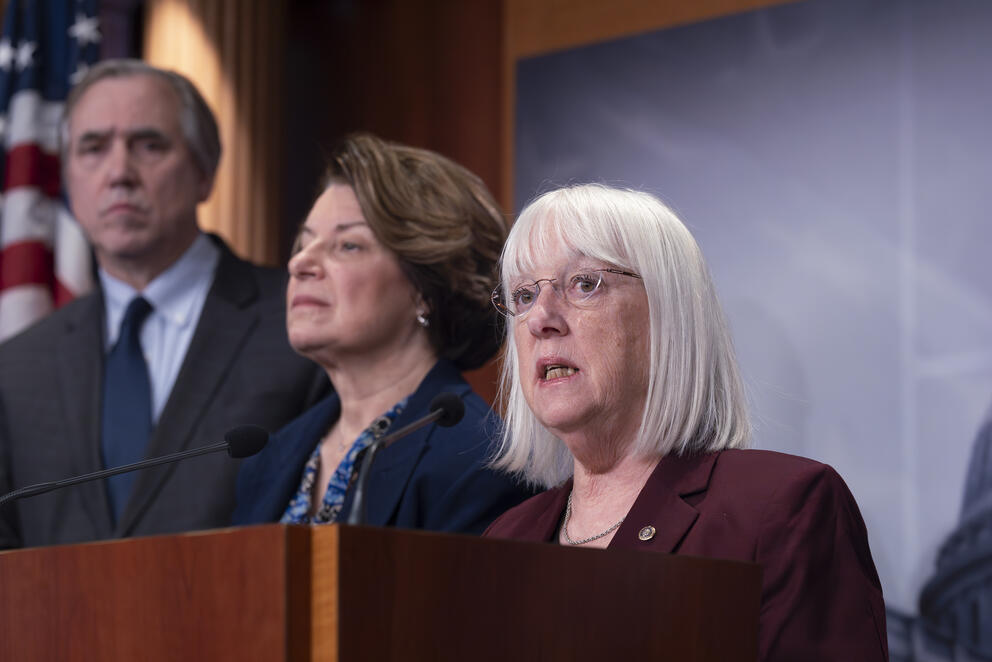 Three people stand behind a podium