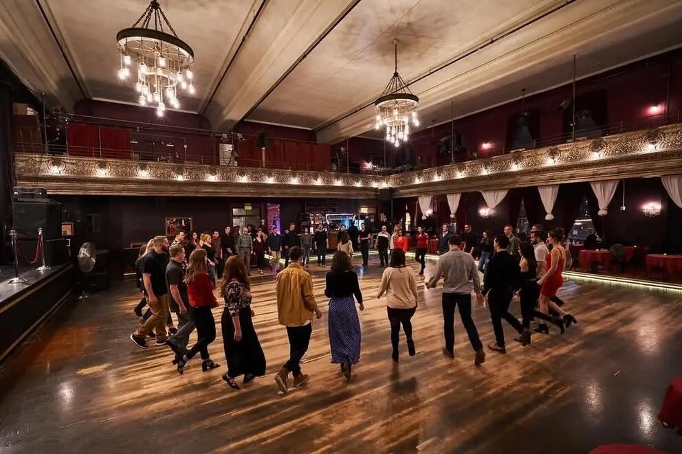 photo of a ballroom with a circle of people dancing in street clothes