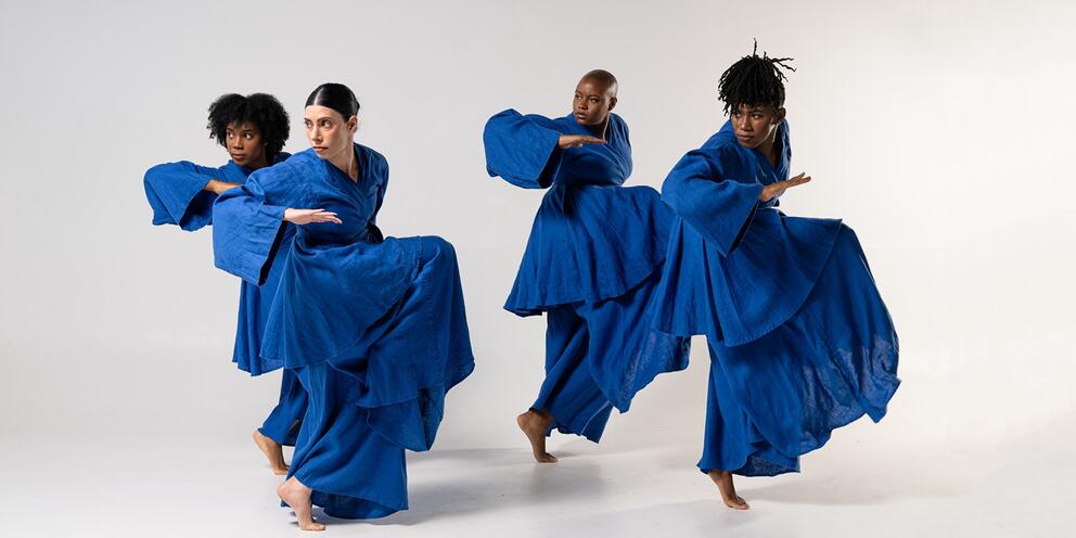 photo of four dancers performing in formation in bright blue dresses