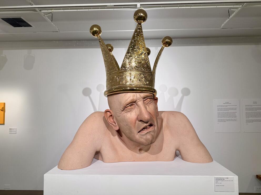 photo of a large sculpture of a man from the shoulders up, older, wearing a giant golden crown