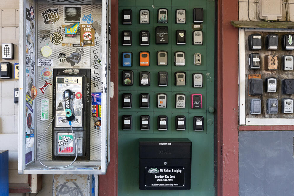 Dozens of key boxes are on a wall next to a phone.