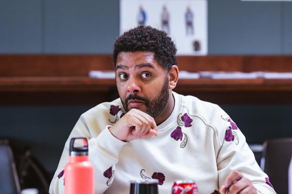 photo of a casually dressed Black man with eyebrows raised, wearing a patterned shirt