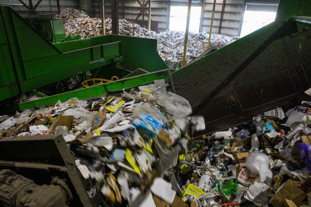 Assorted trash goes through a large machine.