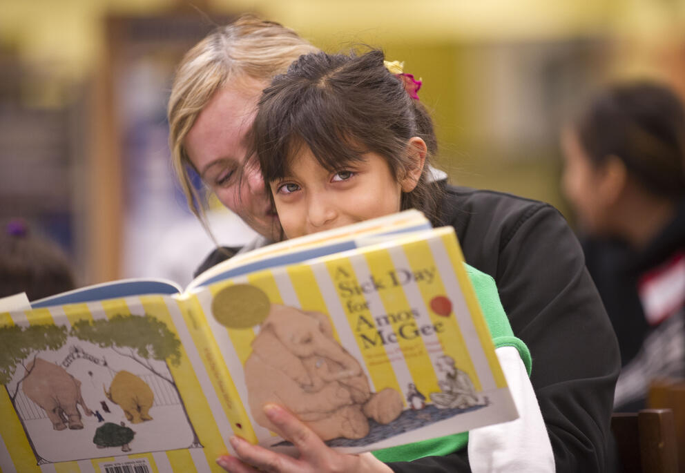 a mother and daughter sit together reading a book