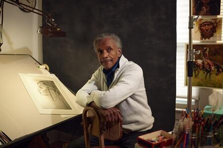 a man poses sitting at a drawing table
