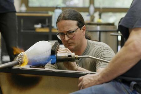 man staring at glass sculpture of salmon
